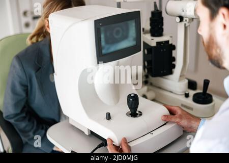Close up of male oculist checking vision for patient with ophthalmic equipment Stock Photo