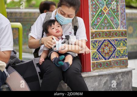 Bangkok, Thailand, february, 16, 2022: woman feeding a baby on the street Stock Photo