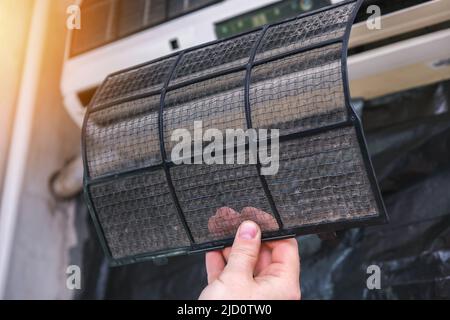 The man takes out filters from the air conditioner for cleaning. Split system maintenance. Stock Photo