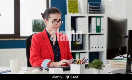 Office employee analyzing research project on computer, planning marketing statistics on business charts to create financial strategy. Executive assistant working at startup company. Stock Photo