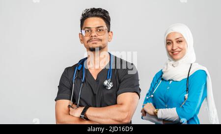 beautiful muslim doctor woman and indian nurse in glasses discuss tasks. portrait of beautiful medical workers with stethoscopes. Medical help, insura Stock Photo