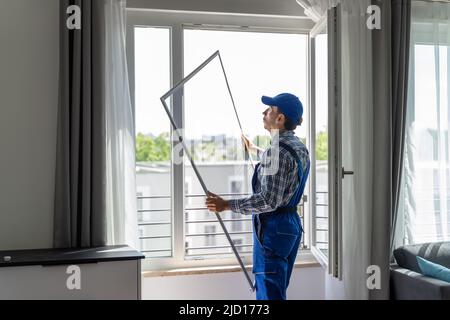 Mosquito Net Frame Install Service. Worker At Home Stock Photo