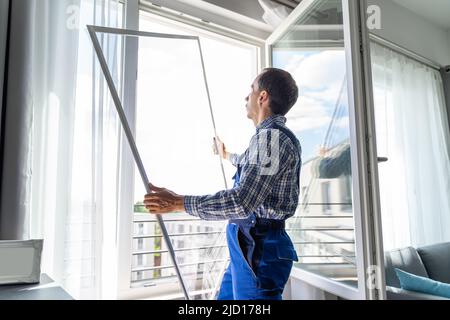 Mosquito Net Frame Install Service. Worker At Home Stock Photo