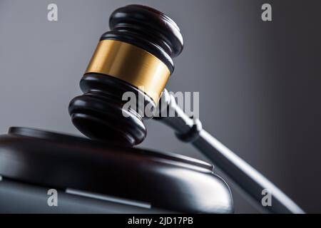 Law theme, mallet of the judge on wooden desk with Lady Justice Statue. Law gavel on dark foggy background with light. Stock Photo