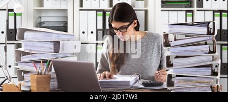 Young Businesswoman Wearing Eyeglasses Calculating Bill In Office Stock Photo