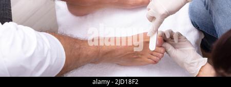 High Angle View Of Beautician Filling Man's Nail In Salon Stock Photo