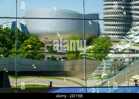 Reflections of the BMW Tower, BMW Museum and Trias Bridge in the glass facade of BMW World Munich, Germany, 15.5.22 Stock Photo