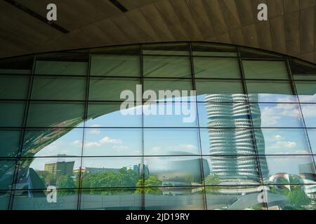 Reflections of the BMW Tower and BMW  Museum in the glass facade of BMW World Munich, Germany, 9.5.22 Stock Photo