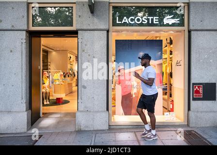 A pedestrian walks past the French clothing brand Lacoste store and logo in Spain Stock Photo Alamy