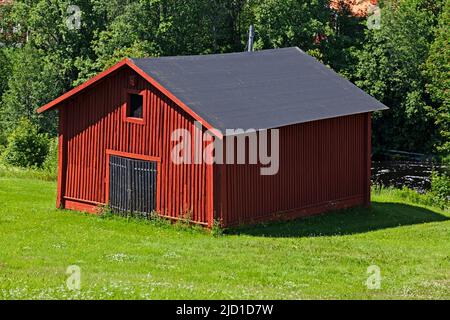 Umea, Norrland Sweden - June 28, 2021: a red picturesque barn by a stream Stock Photo