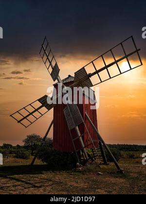 Backlit trestle windmill, dramatic evening sky, Lerkaka mills, Oeland island, Kalmar laen, Sweden Stock Photo