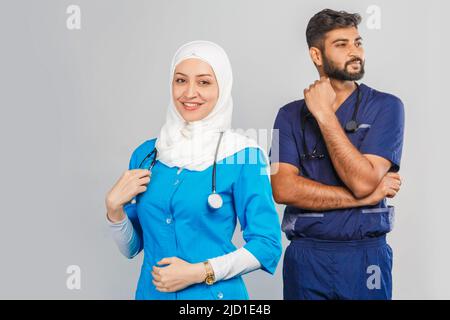 professional muslim doctor woman and indian assistant discuss tasks. portrait of beautiful medical workers with stethoscopes. Medical help, insurance Stock Photo