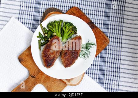 White plate with cutlets on traditional cheched kitchen towel and wood board Stock Photo
