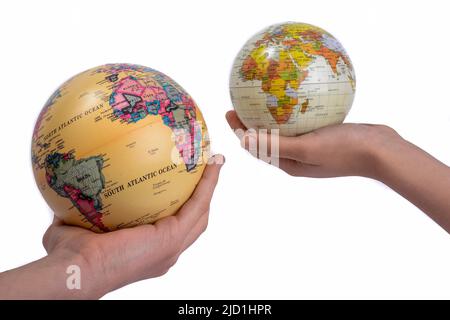 Two hands holding holding two globes in hand on white background Stock Photo