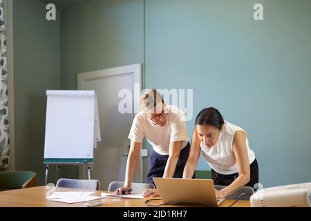 Women in boardroom using laptop Stock Photo