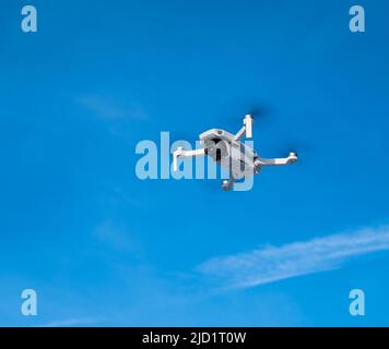 DJI Mavic Mini drone in the air against the blue sky Stock Photo