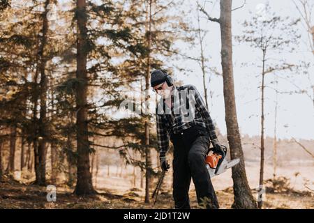 Senior man in forest holding chainsaw Stock Photo