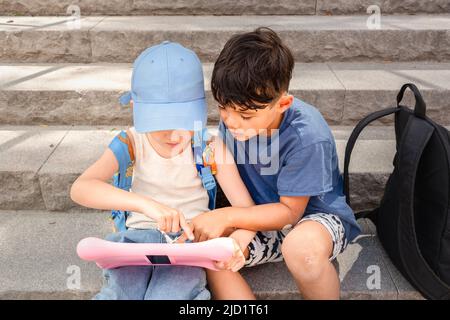 Children sitting on stairs and using tablet Stock Photo