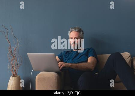 Man with laptop sitting on sofa Stock Photo