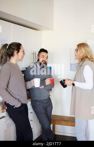 Co-workers talking during coffee break Stock Photo