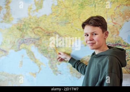 Portrait of boy pointing on map in class Stock Photo