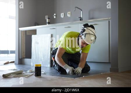 Worker installing floor in kitchen Stock Photo