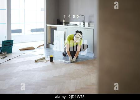Worker installing floor in kitchen Stock Photo