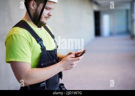 Worker using cell phone at building site Stock Photo