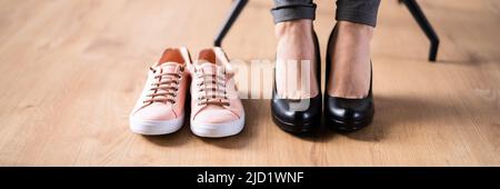 Pair Of A White Sport Shoes Besides Businesswoman's Legs In Office Stock Photo