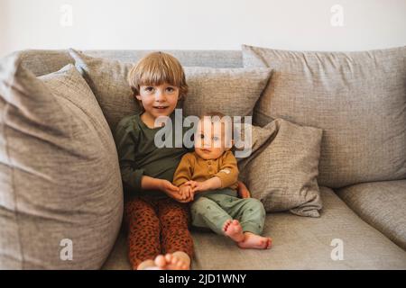 Sibling sitting on sofa Stock Photo