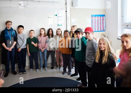 Teacher with students standing in classroom Stock Photo