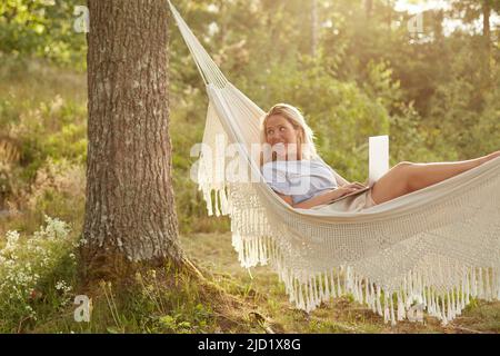 Woman using laptop in hammock Stock Photo