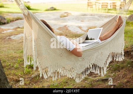 Woman using laptop in hammock Stock Photo