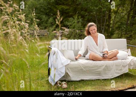 Woman using laptop on garden bench Stock Photo