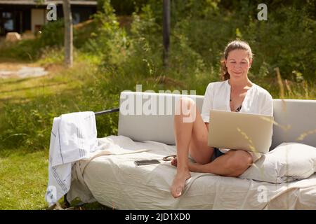 Woman using laptop on garden bench Stock Photo