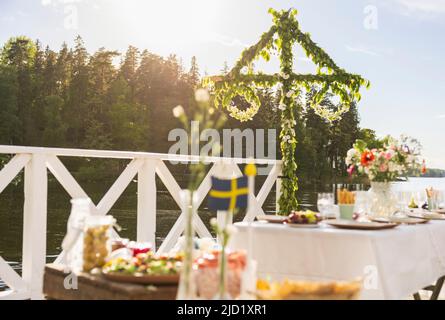 Midsummer maypole and set table by lake Stock Photo
