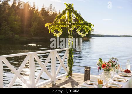 Midsummer maypole and set table by lake Stock Photo