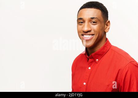 Headshot of friendly optimistic African-American guy in red shirt isolated on white. Smiling kind male student looking at the camera, portrait of employee Stock Photo
