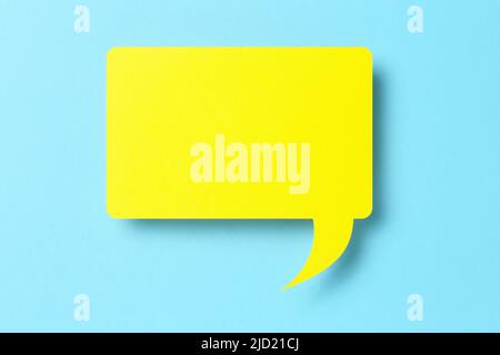 3d yellow paper speech bubble on blue Stock Photo