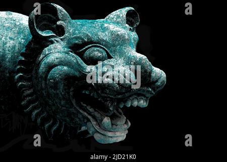 Weathered stone guardian statue head in front of Hindu temple in Bali Indonesia. Black background. Copy Space Stock Photo