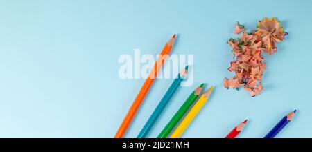 banner with Sharpened colored pencils and pencil shavings on pastel blue color. Rainbow or LGBT pencils. Top view