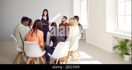 Woman talking to group of young diverse business people during meeting in office Stock Photo