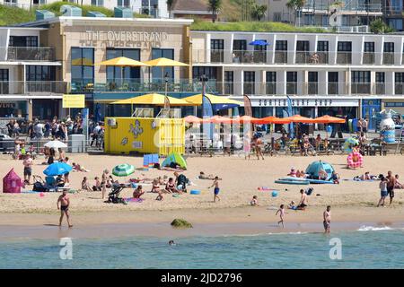 Boscombe, Bournemouth, Dorset, UK, 17th June 2022, Weather. Set to be the hottest day of the year so far as the short heatwave peaks. People head to the beach for the sunshine and some fresher sea air in front of The Overstrand restaurant and surf shop. Credit: Paul Biggins/Alamy Live News