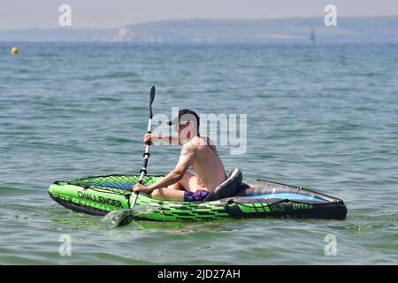 Boscombe, Bournemouth, Dorset, UK, 17th June 2022, Weather. Set to be the hottest day of the year so far as the short heatwave peaks. Man paddling out to sea in an inflatable canoe or kayak. Credit: Paul Biggins/Alamy Live News Stock Photo