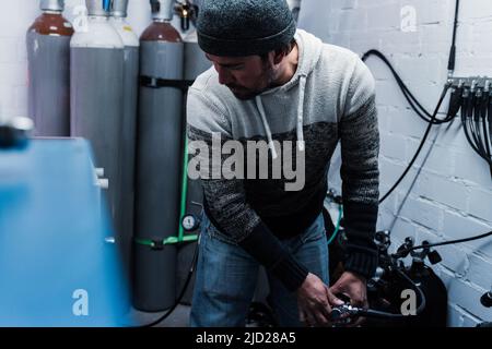 Diver man working inside filling station at diving workshop center - Focus on face Stock Photo