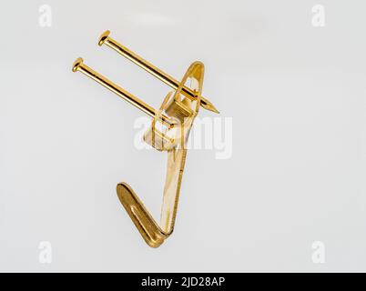 close up floating image of a double fixing single hook brass  metal wall mounted picture hook Stock Photo