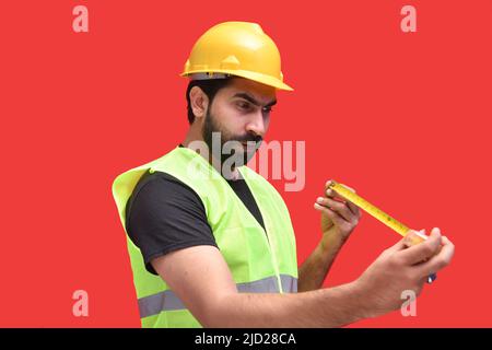 construction worker holding inch tape and measuring size with expression posing side Stock Photo