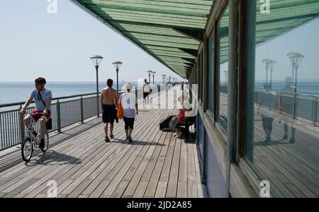 People make their way along Boscombe Pier in Dorset. A sweltering 34C (93.2F) is expected in London and potentially some spots in East Anglia on Friday, according to the Met Office. Picture date: Friday June 17, 2022. Stock Photo