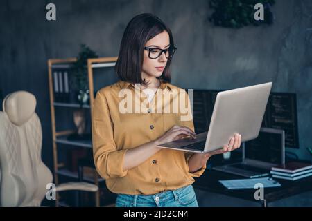 Portrait of attractive focused skilled girl expert typing email editing project task at workplace workstation indoors Stock Photo