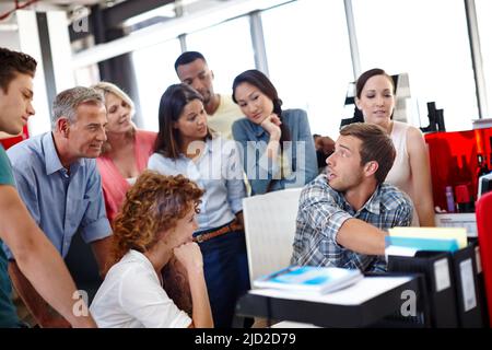 Thats all you need. Shot of a young man explaining something to his colleagues in the office. Stock Photo